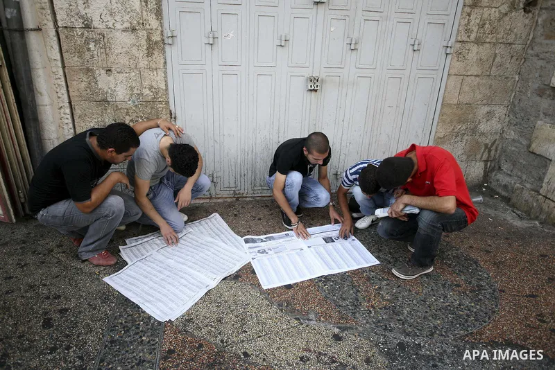 Palestinian general secondary students read a local newspaper to find their results in the West Bank city of Ramallah on July 22, 2010. Photo by Eyad Jadallah