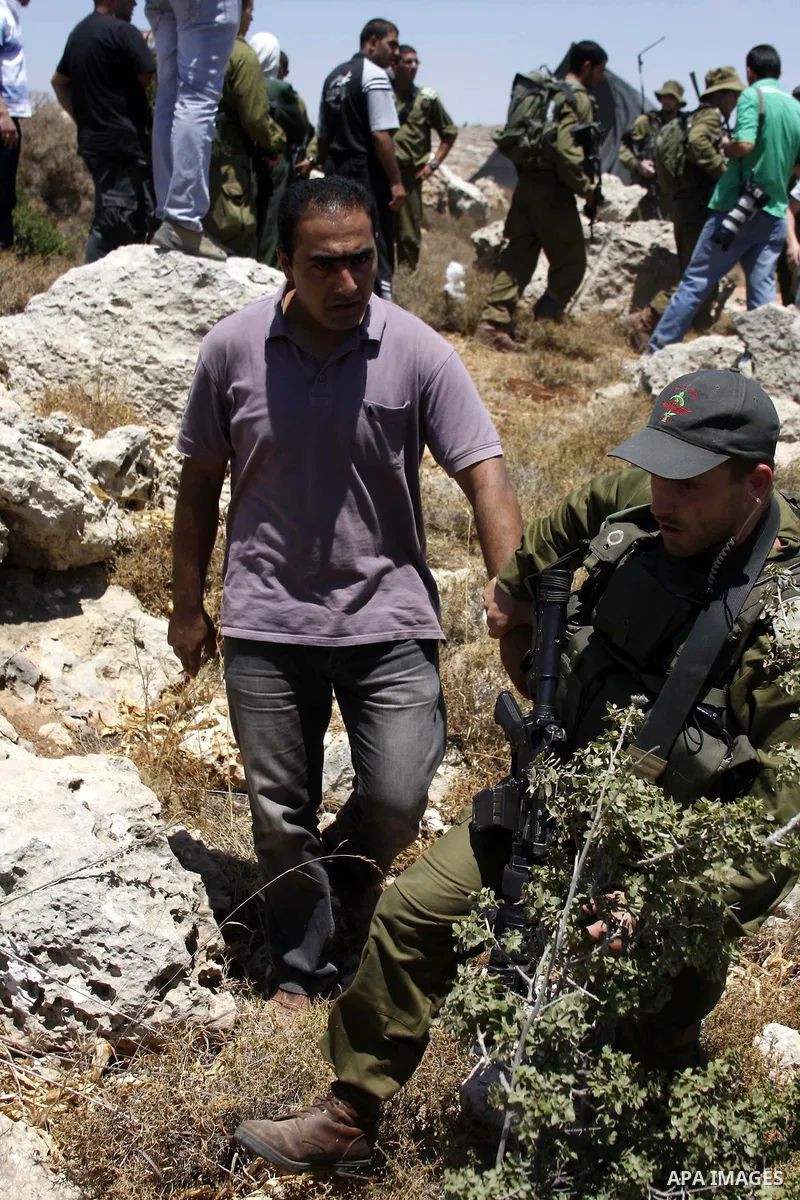 A Palestinian man argues with Israeli forces as he is taken away from his land which has been occupied by tents of armed Jewish ideological settlers (unseen) who are setting up a new outpost near the Israeli settlement o...