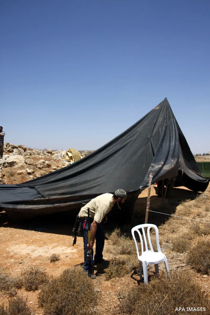 Armed Jewish ideological settlers set up tents on Palestinian land as they try to establish a new outpost near the Israeli settlement of Kharsina on 23 July 2010 east of Hebron, in the occupied West Bank. Photo by Mamoun...