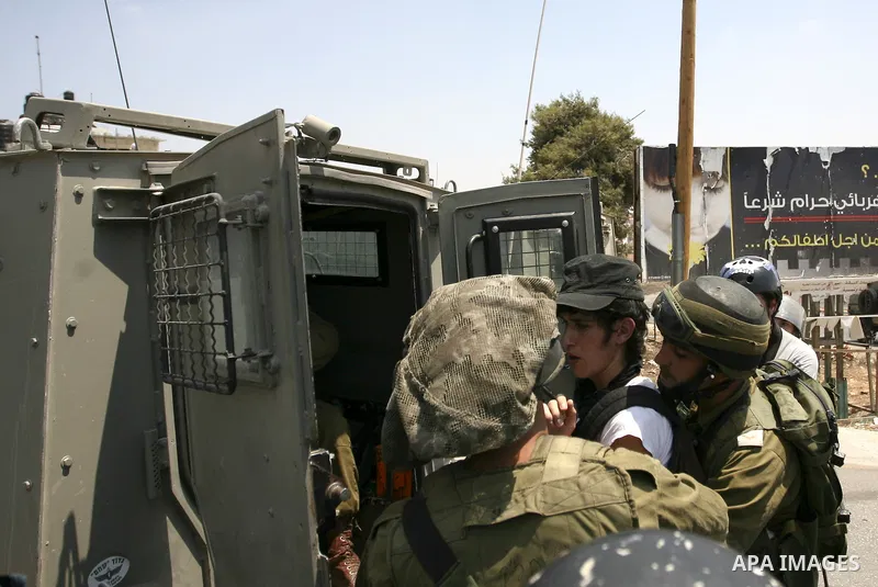 Israeli soldiers detain a demonstrator during a protest against the expansion of the nearby Jewish settlement of Halamish in the West Bank village of Nabi Saleh, Friday, July 23, 2010. Photo by Eyad Jadallah