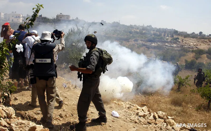 Protesters run for cover from tear gaz canister fired by Israeli soldiers during a demonstration against Israel's controversial separation barrier in the village of Beit Omar near Jewish settlement of Karmi zur near the...