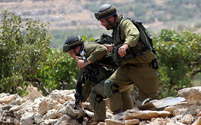 An Israeli soldier helps a wounded soldier during a demonstration against Israel's controversial separation barrier in the village of Beit Omar near Jewish settlement of Karmi zur near the West Bank city of Hebron, on 24...