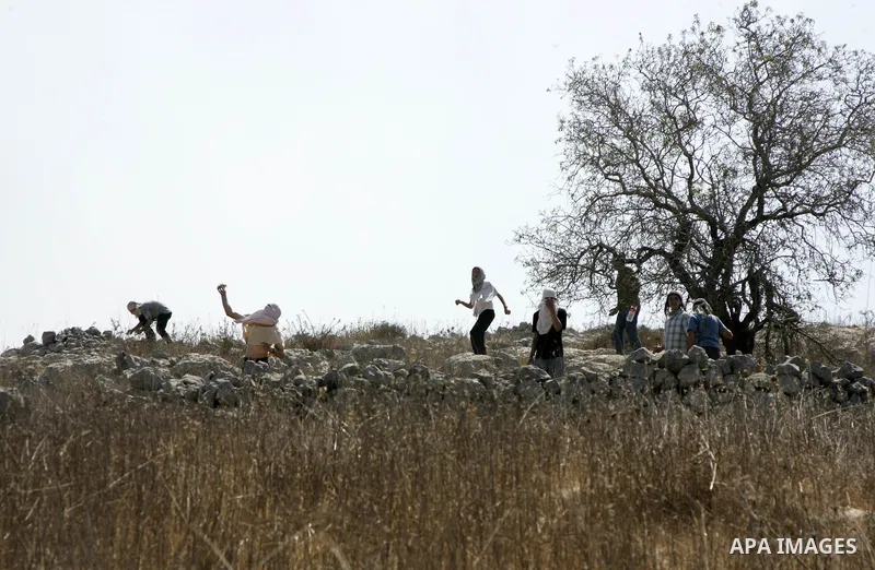Jewish settlers sling rocks towards Palestinians during clashes close to the northern West Bank village of Burin on July 26, 2010, which began when Israeli troops removed two mobile homes set up near the Bracha settlemen...