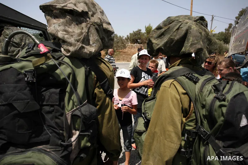 Israeli soldiers stand guards past Palestinian, Israeli and international activists during a demonstration against the expansion of the nearby Jewish settlement of Halamish in the West Bank village of Nabi Saleh near Ram...
