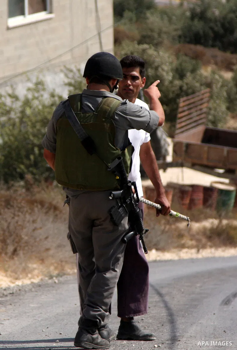 Israeli soldiers scuffle with Palestinian men who work to quell a fire started by Israeli settlers on the outskirts of Burin village, near the Jewish West Bank settlement of Yitzhar, near Nablus, Friday July 30, 2010. Ph...