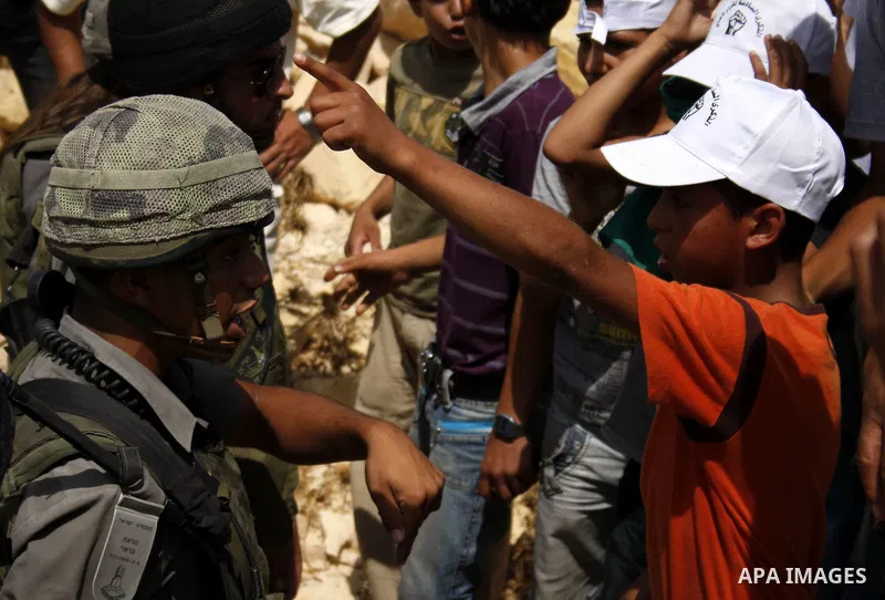 An Israeli soldier scuffles with a Palestinian boy during a demonstration against Israel's controversial separation barrier in the village of Beit Omar near Jewish settlement of Karmi zur near the West Bank city of Hebro...