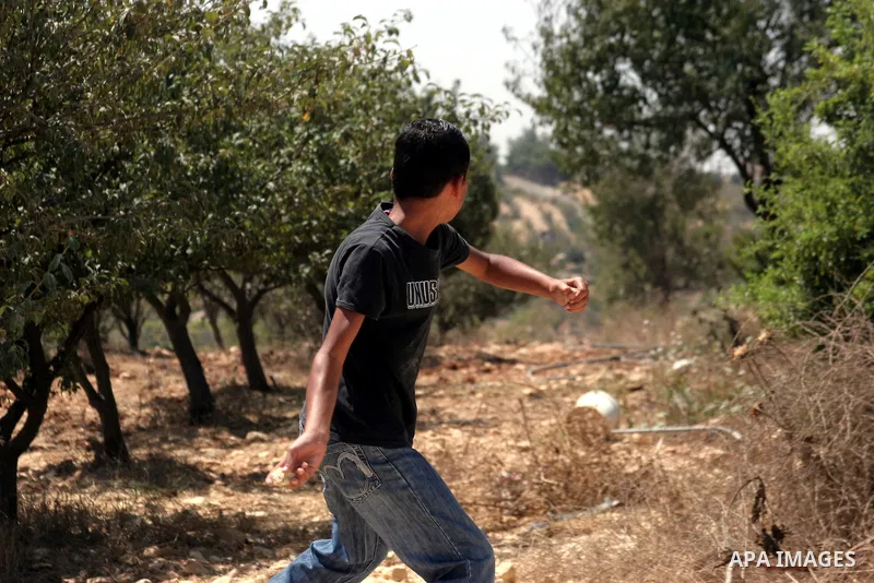 A Palestinian boy throws stones at Israeli soldiers during a demonstration against Israeli settlements, in the West Bank village of Beit Omar, near Hebron, Saturday, on August 7, 2010.. Photo by Mamoun Wazwaz