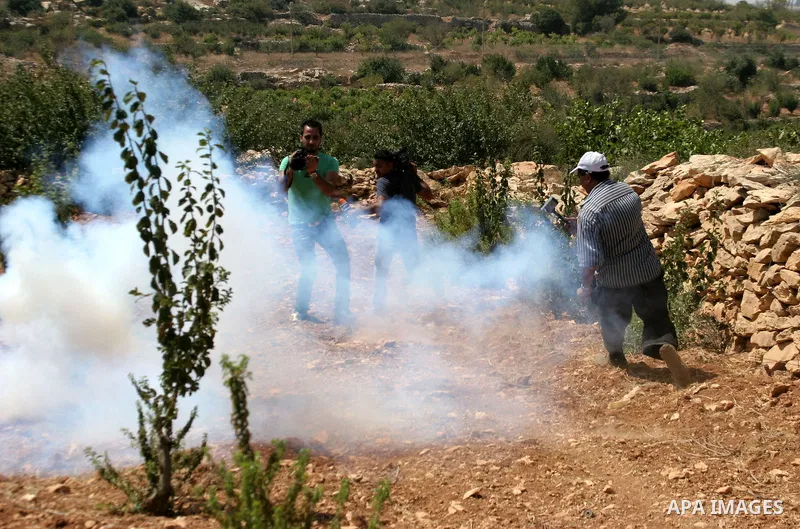 Palestinian protesters and journalists run to take cover from tear gas canisters fired by Israeli soldiers during a demonstration against Israeli settlements, in the West Bank village of Beit Omar, near Hebron, Saturday,...