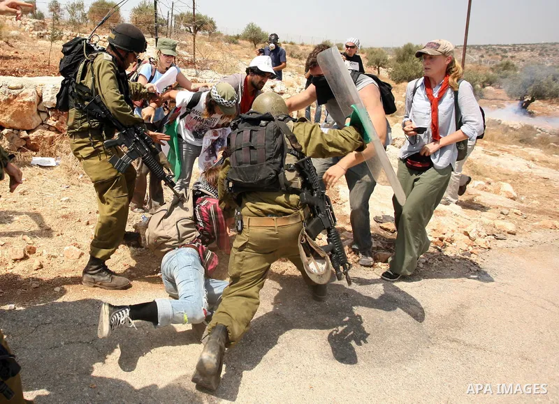 Israeli soldiers detain a protestor during a demonstration against pictures of troops posing with handcuffed Palestinian prisoners posted on Facebook, on August 20, 2010 in the West Bank village of Bilin. Photo by Eyad J...