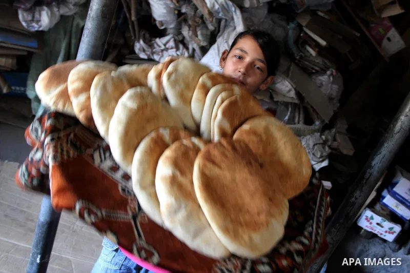A Palestinian girl carrying loaves of bread at traditional bakery in Gaza City on August 29,2010 . Photo by Ashraf Amra