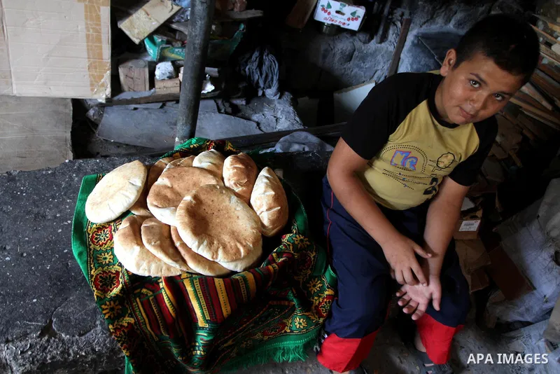 A Palestinian boy sit near loaves of bread at traditional bakery in Gaza City on August 29,2010 . Photo by Ashraf Amra