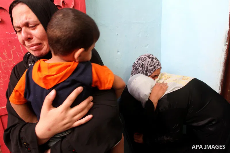 Palestinian female relatives of Suleiman al-Hatab, 22-years-old, one of two Palestinian men killed, weep as his body is taken away from his home during his funeral in the al-Bureij refugee camp in the central Gaza strip,...