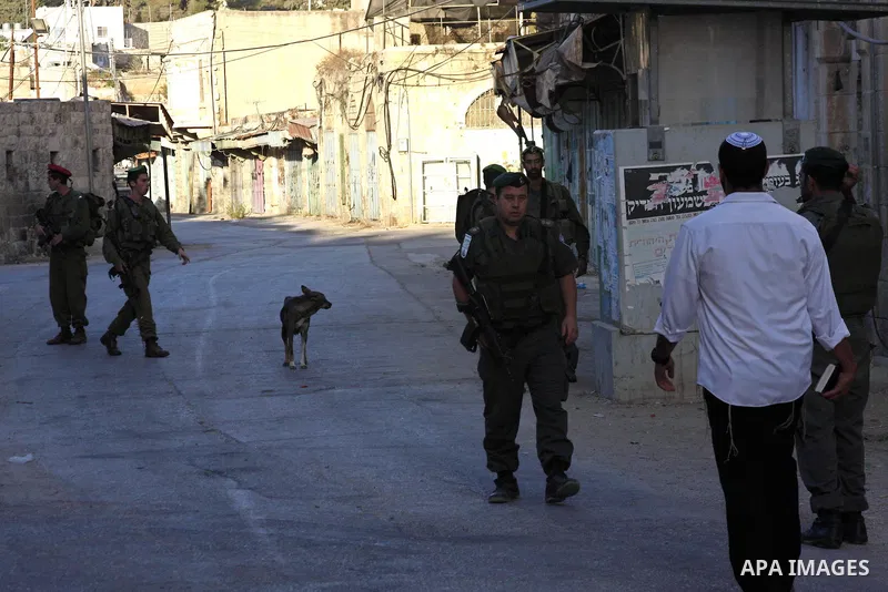 An Israeli settler walks past police guards to the Tomb of the Patriarchs for morning Rosh Hashana (Jewish New Year) prayers, on Sept. 10, 2010, in the West bank town of Hebron, where Palestinian Muslims also pray at the...