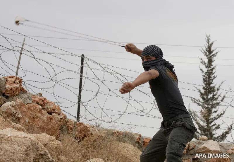 A Palestinian protestor uses a sling-shot to hurl a stone at Israeli troops during a protest against Israel's separation barrier in the West Bank village of Bilin near Ramallah, Friday, Sept. 17, 2010. Israel says the ba...