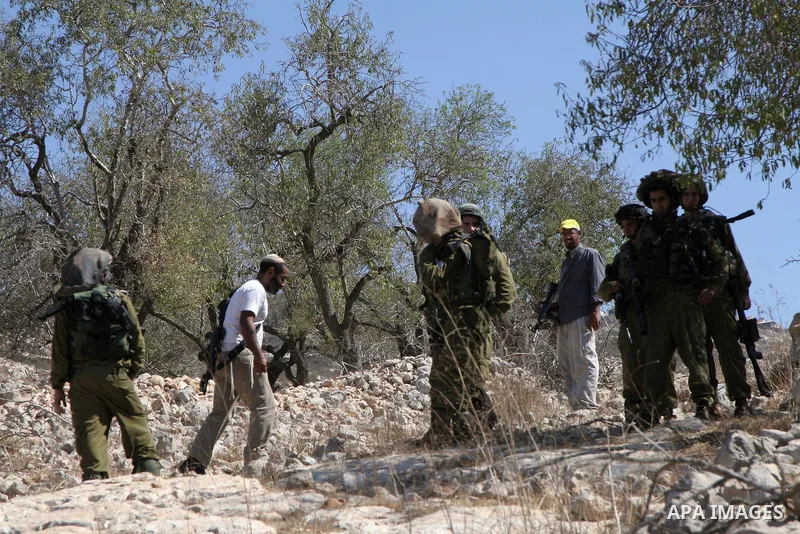 Israeli soldiers stand guard as Jewish settlers in the agricultural fields in the village of Burin, near Nablus in the West Bank , Monday, Sept. 2010 . Palestinian farmers said the Israelis settlers from the settlement o...