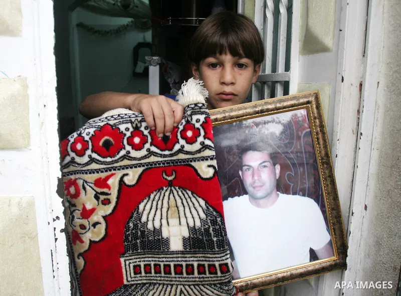 Palestinian boy carries a picture to his father Samir Serhan during his funeral precession on September 22, 2010 in the east Jerusalem neighborhood of Silwan after the Palestinian father of six was shot dead overnight by...