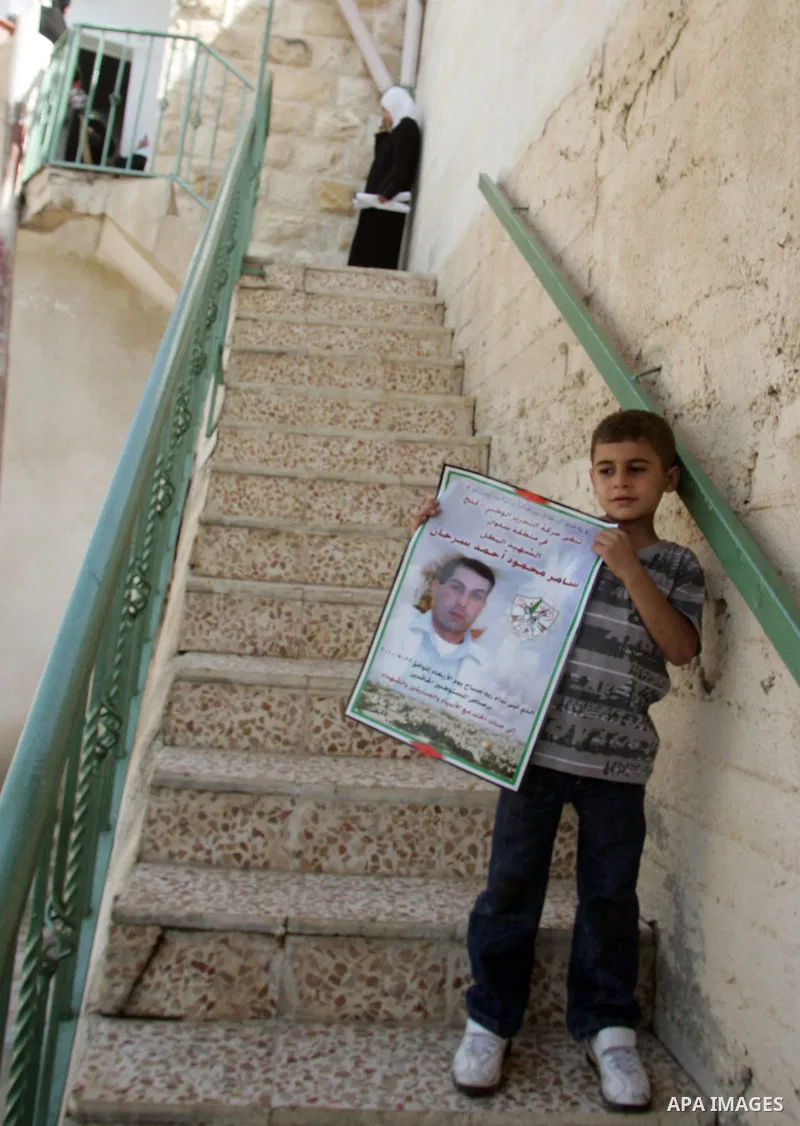 Five-year-old Sultan and his sister Aya, two of six children of Samir Sarhan, hold posters with the picture of their father who was shot dead the day before by a Jewish settlement guard, at the family house in the Arab e...