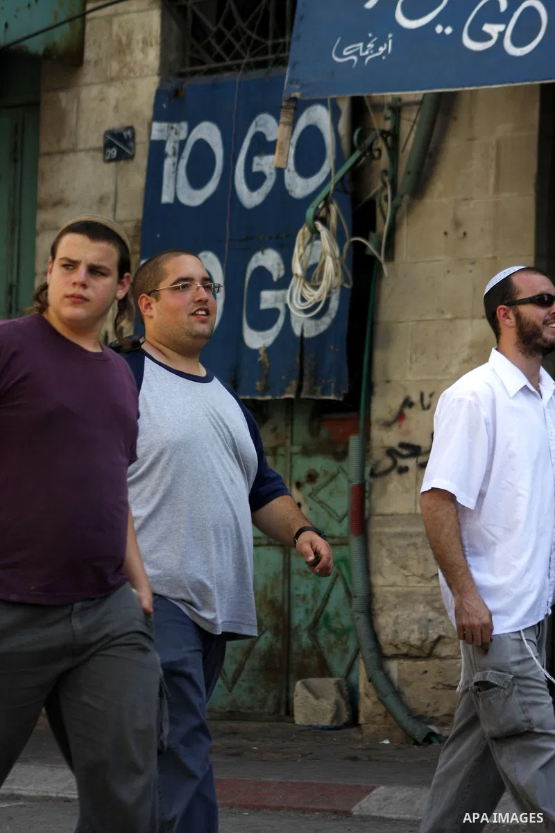 Israeli settlers are escorted by Israeli troops inside the old city of the West Bank town of Hebron on 26 September 2010. A large group of right-wing Jews toured the area with Israeli soldiers escort on the day when the...