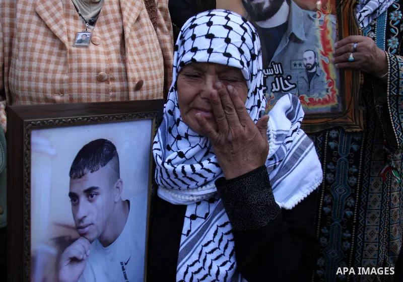 A Palestinian woman crying on her son while she hold pictures of relatives, held in Israeli jails, during a protest calling for their release in the West Bank city of Nablus, Wednesday on Sept. 29, 2010 . Photo by Wagdi...