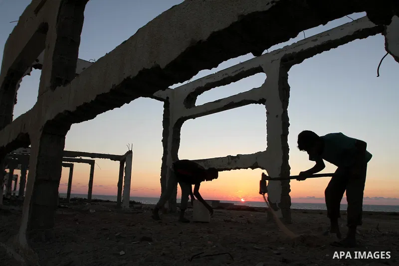 Palestinians work to re-manufacture cement from the remains of ruins of Palestinian buildings that were destroyed during the Israeli war against Hamas in the Gaza Strip, in the west of Beit Lahiya town in the northern Ga...