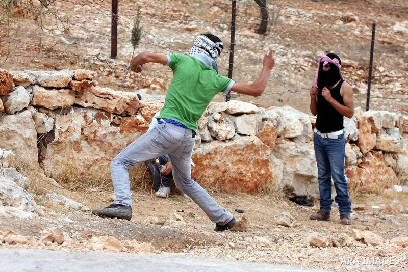 A Palestinian youth hurls stones at Israeli forces during the clashes following a weekly demonstration against Israel's separation barrier in the West Bank village of Bilin, near Ramallah, on Oct. 8, 2010. Photo by Eyad...