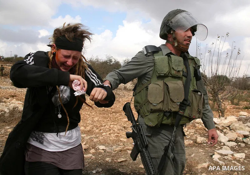 An Israeli border policeman detains a foreign protester after she was sprayed with colored pepper spray during a demonstration by Palestinian, Israeli and foreign activists against the demolishing of farm land to be used...