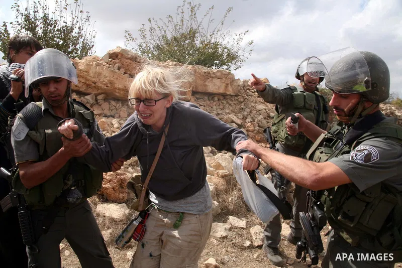 An Israeli border policeman detains a foreign protester after she was sprayed with colored pepper spray during a demonstration by Palestinian, Israeli and foreign activists against the demolishing of farm land to be used...
