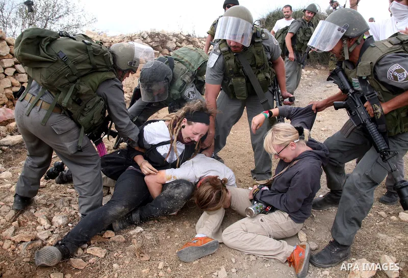 Israeli border policemen detain foreign protesters after she was sprayed with colored pepper spray during a demonstration by Palestinian, Israeli and foreign activists against the demolishing of farm land to be used in t...