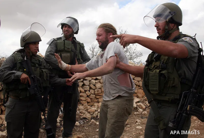 An Israeli border policeman detains a foreign protester after she was sprayed with colored pepper spray during a demonstration by Palestinian, Israeli and foreign activists against the demolishing of farm land to be used...