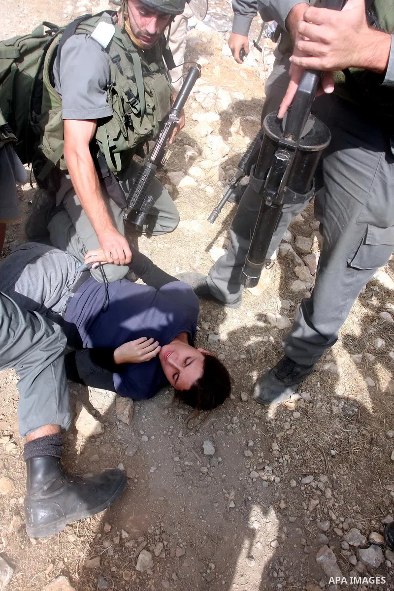 An Israeli border policeman detains a foreign protester after she was sprayed with colored pepper spray during a demonstration by Palestinian, Israeli and foreign activists against the demolishing of farm land to be used...