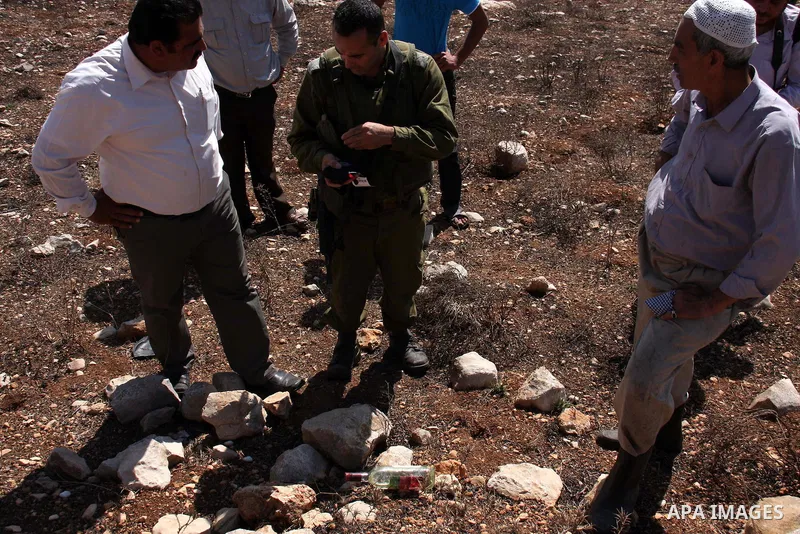 An Israeli soldier talks with Palestinians who attacked by Jewish settlers during pick olives in their agricultural fields in the West Bank village of Hawara, near Nablus. Oct. 10, 2010. Jewish settlers attacked Palestin...