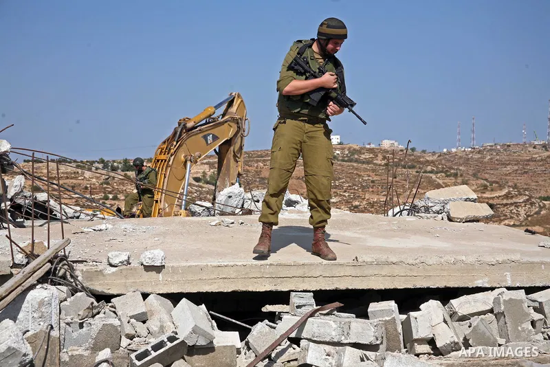 An Israeli soldier stands guard during the demolition operation of a Palestinian house and water wells that belong to Rugby family , just east of the West Bank town of Hebron on October 11,2010 . Photo by Najeh Hashlamou...