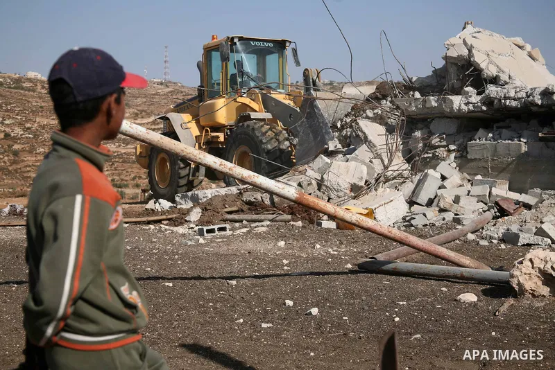 A Palestinian boy looks at an Israeli army bulldozer destroying a Palestinian house and water wells that belong to Rugby family , just east of the West Bank town of Hebron on October 11,2010 . Direct peace talks between...
