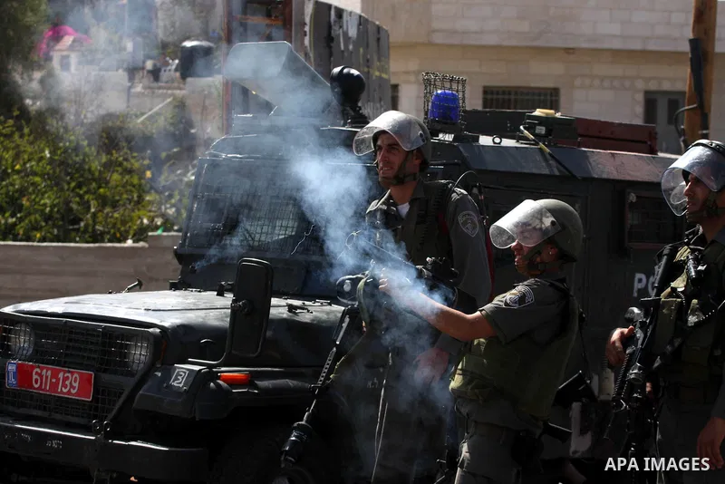 An Israeli soldier fires tear gas canister at Palestinians and foreign activists during a demonstration against the expansion of the nearby Jewish settlement of Halamish in the West Bank village of Nabi Saleh, Friday, Oc...
