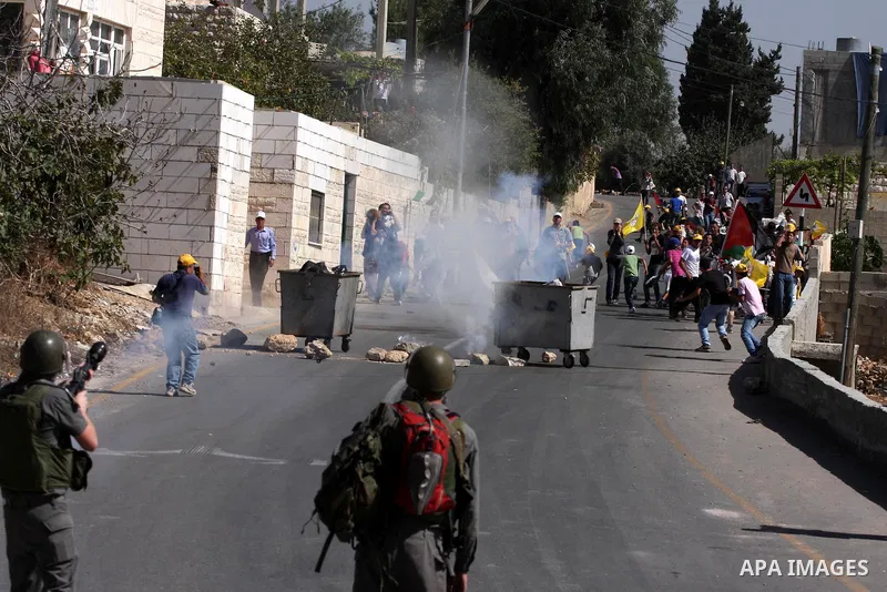 Palestinians and foreign activists run for cover from tear gas canister fired by Israeli soldiers during a demonstration against the expansion of the nearby Jewish settlement of Halamish in the West Bank village of Nabi...