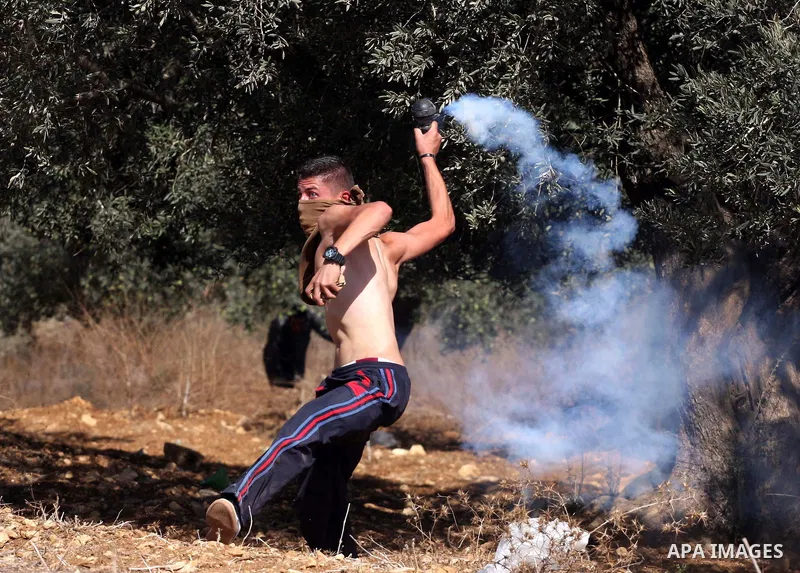 A Palestinian youth hurls return a tear gas canister towards Israeli soldiers during a demonstration against the expansion of the nearby Jewish settlement of Halamish in the West Bank village of Nabi Saleh, Friday, Oct 1...