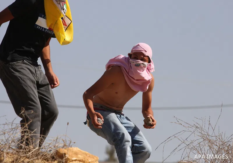 A Palestinian youth hurls stones towards Israeli soldiers during a demonstration against the expansion of the nearby Jewish settlement of Halamish in the West Bank village of Nabi Saleh, Friday, Oct 15, 2010. Photo by Is...