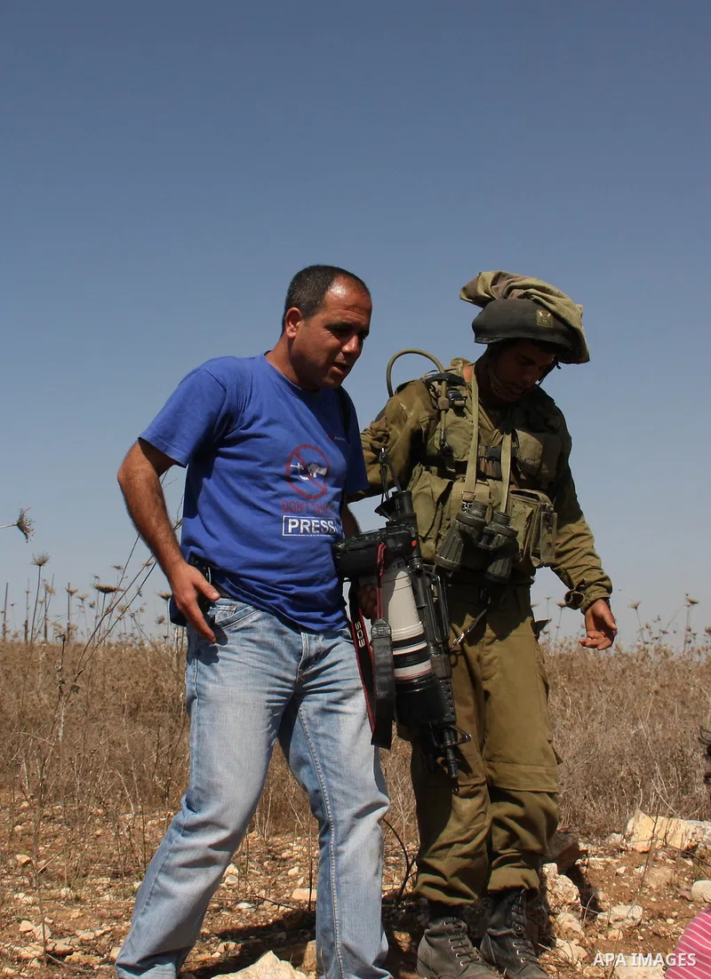 A Palestinian photographer is detained by Israeli soldiers after they arrive to pacify the situation after Israeli settlers attacked Palestinian farmers while they collect Olive at Azmout village near the West Bank City...