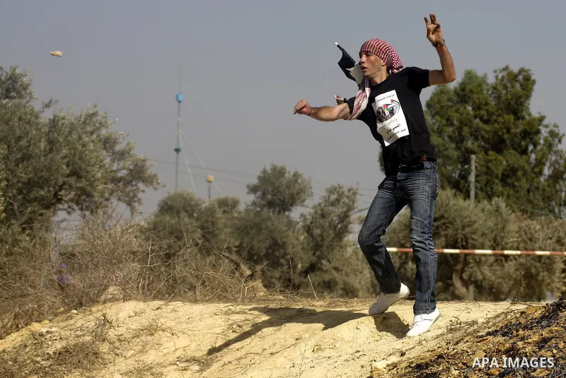 A Palestinian youth hurls stones towards Israeli soldiers during a demonstration against the expansion of the nearby Jewish settlement of Halamish in the West Bank village of Nabi Saleh, Friday, Oct 15, 2010. Photo by Ey...