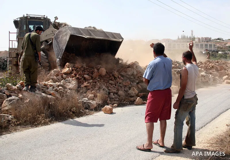 Palestinians argue with Israeli soldiers as Israeli bulldozers work at the back side of the Israeli settlement of Kiryat Arba near Kharsina sattlemen outside the West Bank city of Hebron on October 17, 2010 . Photo by Na...