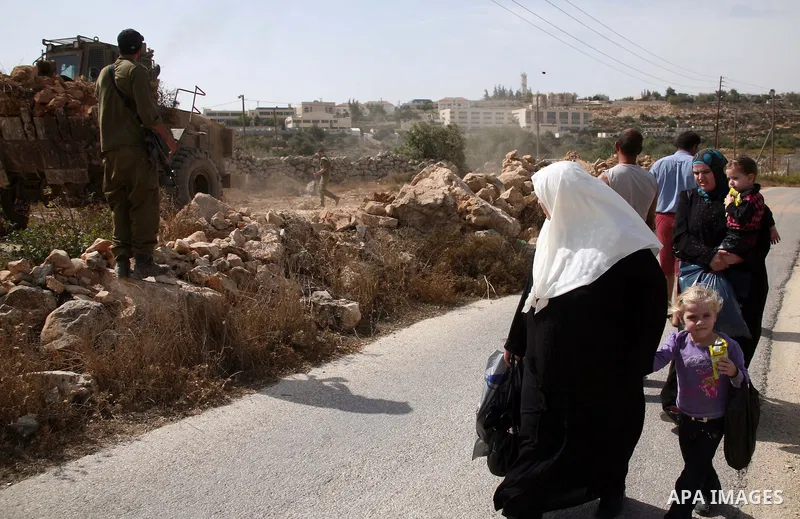 Palestinians walk past Israeli bulldozers working at the back side of the Israeli settlement of Kiryat Arba near Kharsina settlement outside the West Bank city of Hebron on October 17, 2010 . Photo by Najeh Hashlamoun