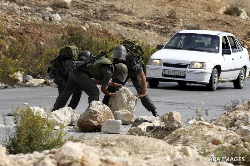 Israeli border policemen carry away stones from a street during clashes in the West Bank village of Nabi Saleh, on 22 October 2010. Palestinians protest weekly against the neighbouring Jewish settlement of Halamish. Phot...
