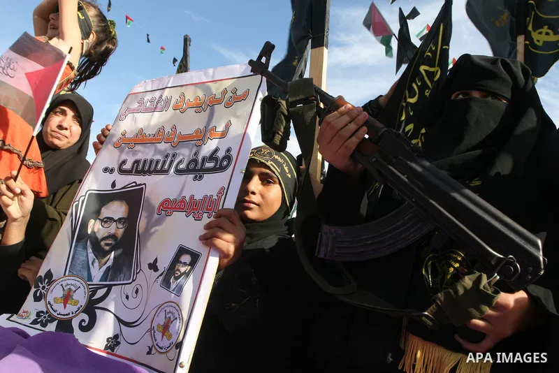 An Islamic Jihad supporter holds a rifle during rally to mark the 23rd anniversary of the establishment of the Islamic Jihad movement and the assassination of the founder of their movement Fathi Shiqaqi , in Gaza city on...