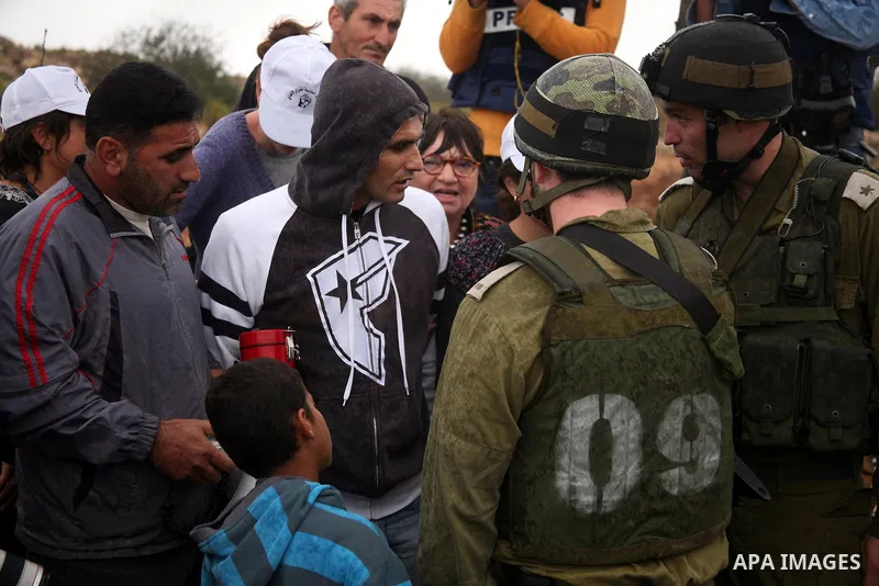 Israeli soldiers stand guard during a demonstration by Palestinian, Israeli and foreign activists against the demolishing of farm land to be used in the construction of Jewish settlements near the existing Israeli settle...