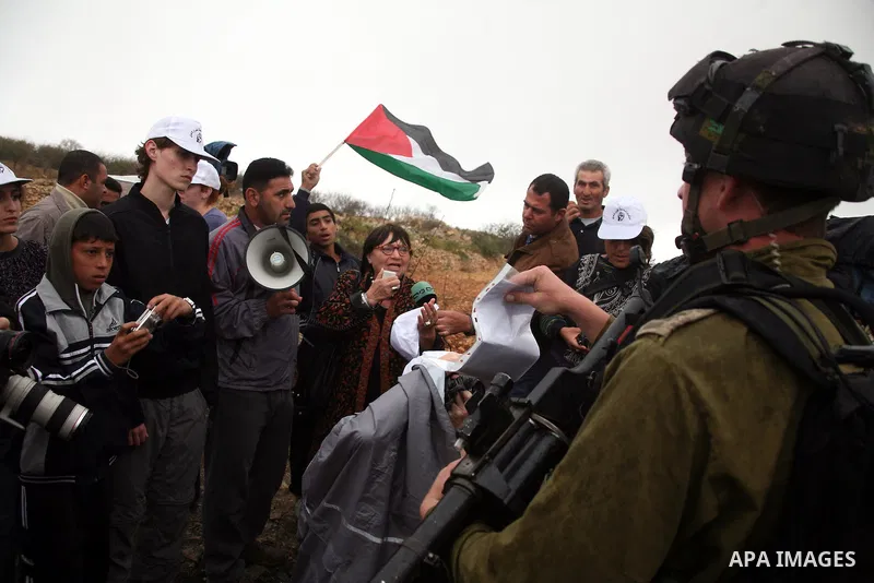 Israeli soldiers stand guard during a demonstration by Palestinian, Israeli and foreign activists against the demolishing of farm land to be used in the construction of Jewish settlements near the existing Israeli settle...