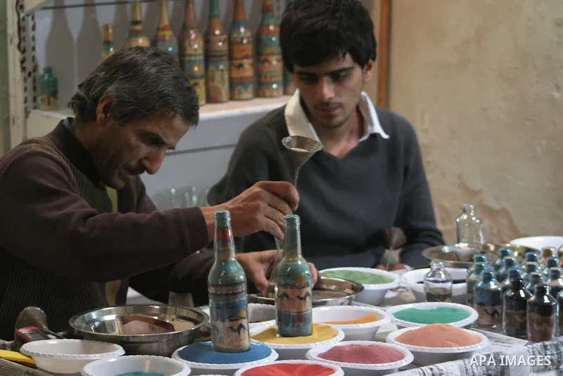 The painter , Mohammed Awawdeh and his assistant paint with sand in a suburb of the Old City of Hebron on Oct. 31,2010 . Awawdeh tries through his drawings is promotion and support the tourism in the old town and enters...