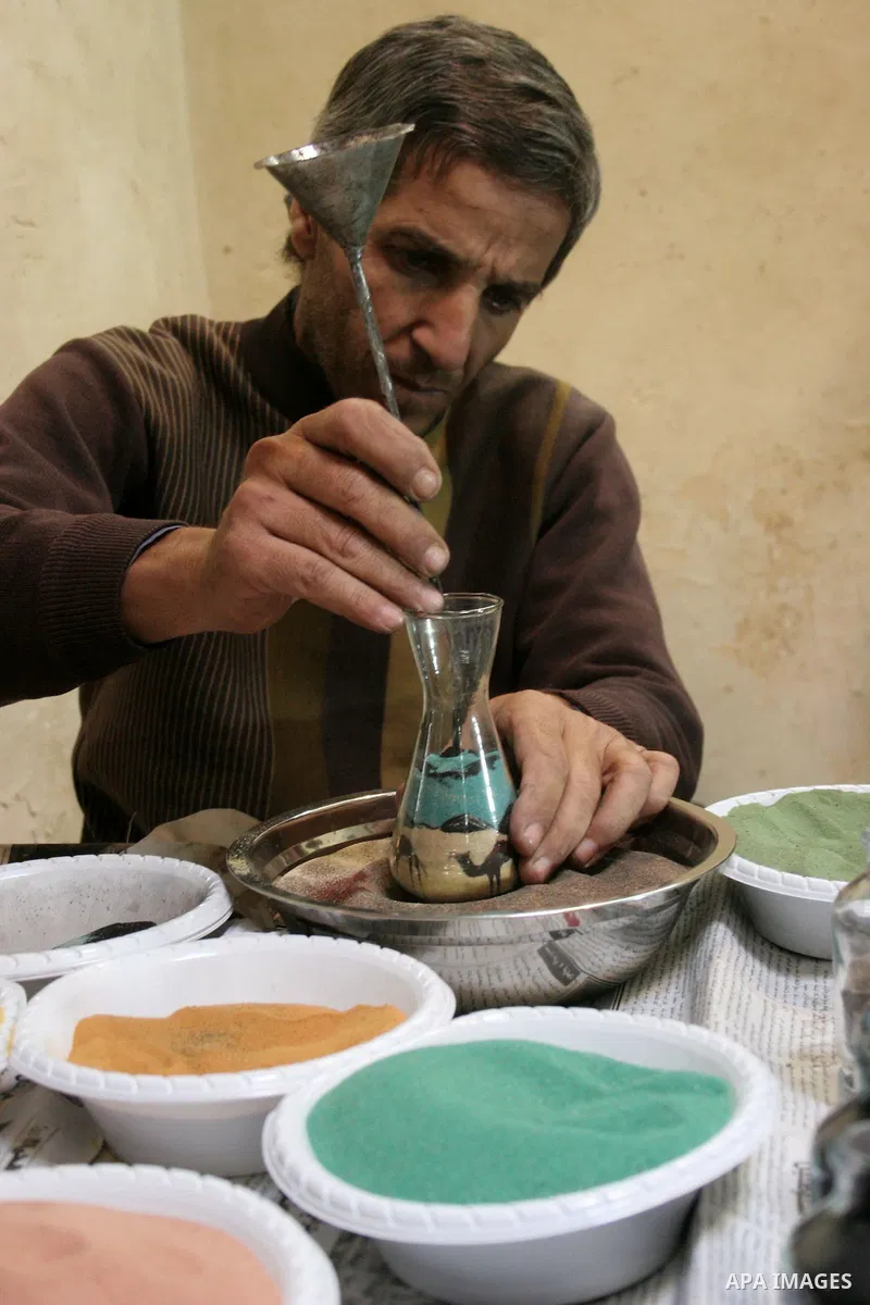 The painter , Mohammed Awawdeh and his assistant paint with sand in a suburb of the Old City of Hebron on Oct. 31,2010 . Awawdeh tries through his drawings is promotion and support the tourism in the old town and enters...