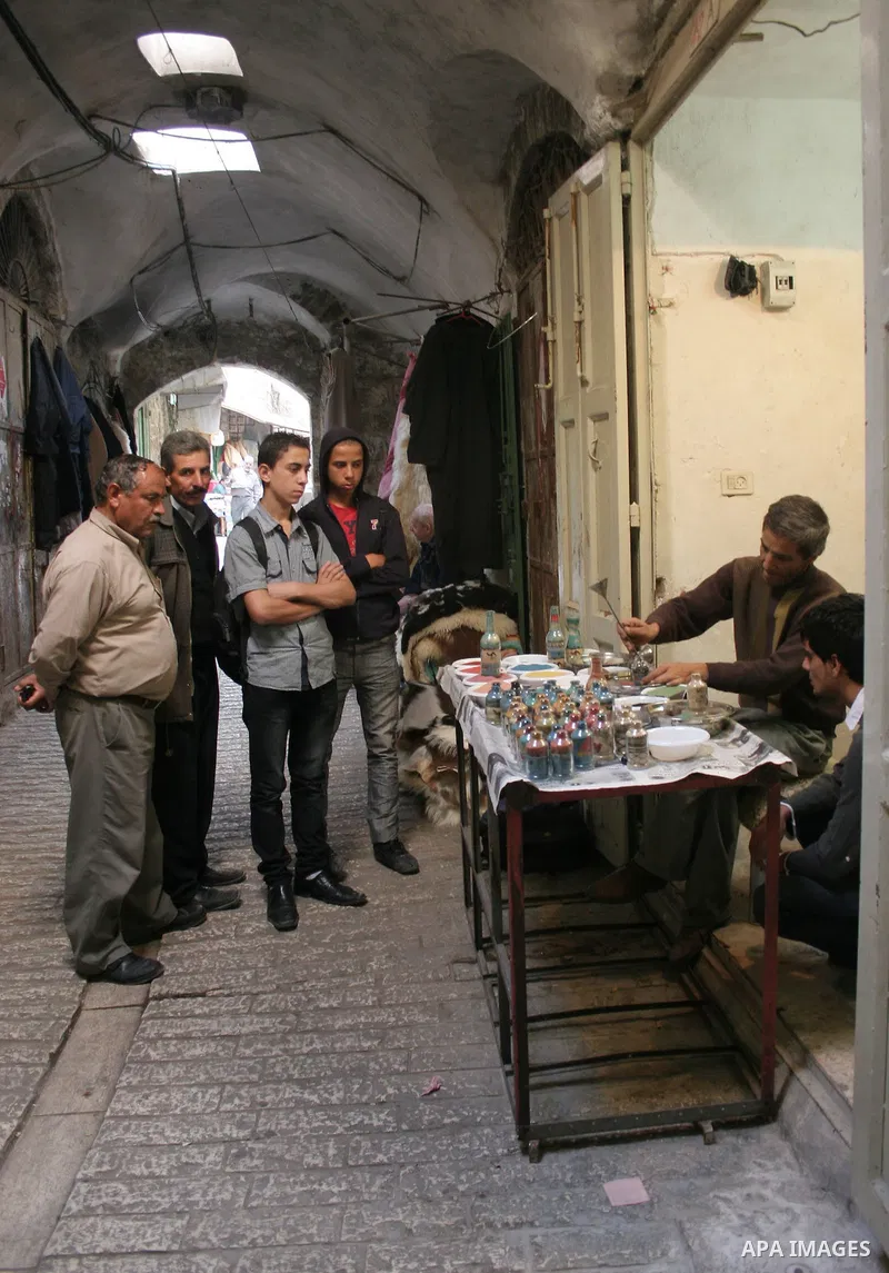 The painter , Mohammed Awawdeh and his assistant paint with sand in a suburb of the Old City of Hebron on Oct. 31,2010 . Awawdeh tries through his drawings is promotion and support the tourism in the old town and enters...