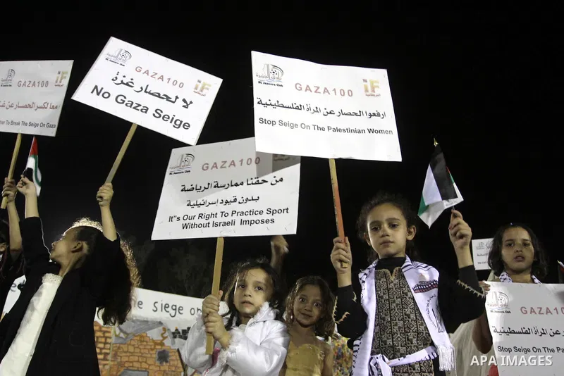 Palestinian girls hold banners written with slogans against the siege on Gaza during a celebrate in winning on the four British cities in the athlete race, in Gaza City on Oct. 31,2010 . "GAZA 100" aspire to has more tha...