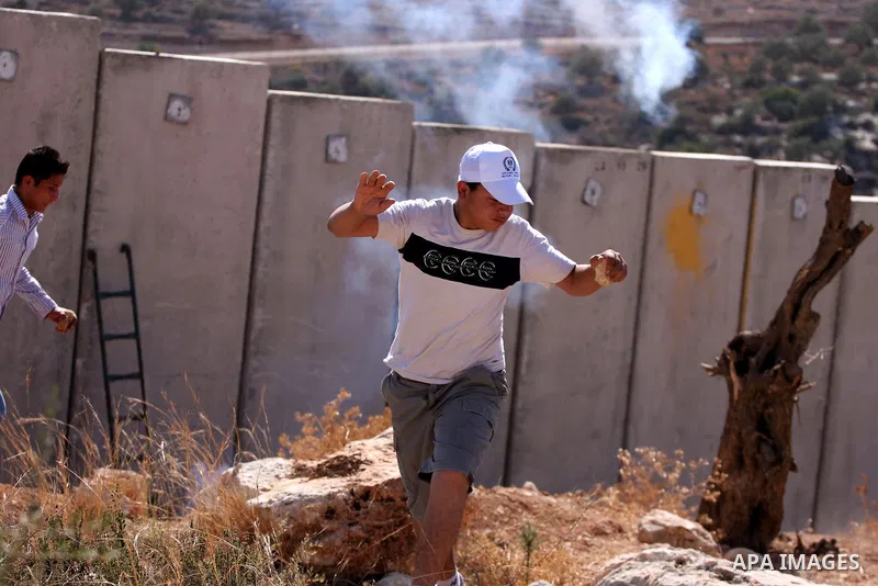 A Palestinian protester run for cover from tear gas fired by Israeli soldiers during clashes in the West Bank village of Nilin, near the Palestinians city of Ramallah,on Nov. 5, 2010. Clashes erupted during the weekly de...
